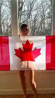 Молодая тян с красивой грудью с флагом Канады позирует через его прозрачную ткань